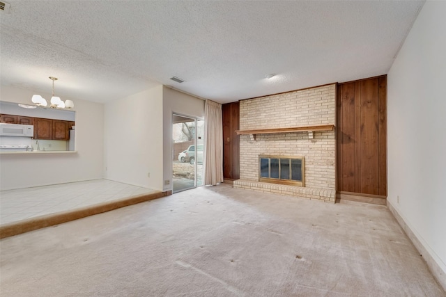 unfurnished living room featuring an inviting chandelier, light carpet, a textured ceiling, wooden walls, and a fireplace