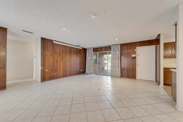 spare room featuring light tile patterned floors, wooden walls, and a textured ceiling