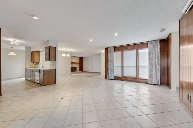 unfurnished living room with an inviting chandelier, sink, a fireplace, and a textured ceiling