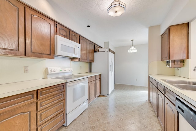 kitchen featuring sink, pendant lighting, a textured ceiling, and white appliances