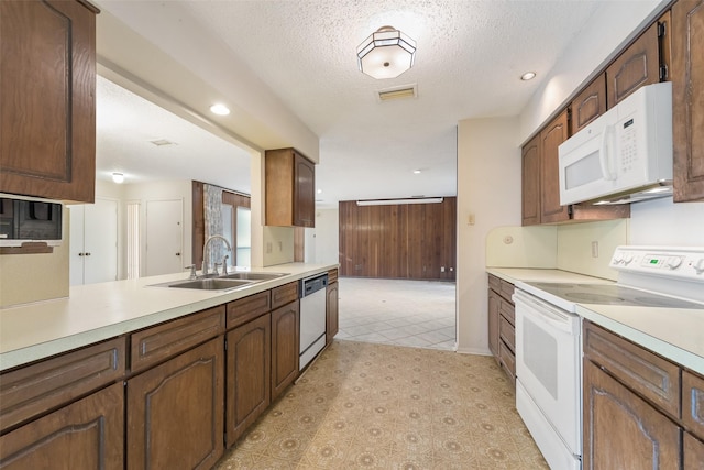 kitchen featuring white appliances, kitchen peninsula, sink, and a textured ceiling