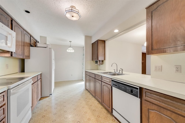 kitchen with sink, white appliances, hanging light fixtures, a textured ceiling, and kitchen peninsula