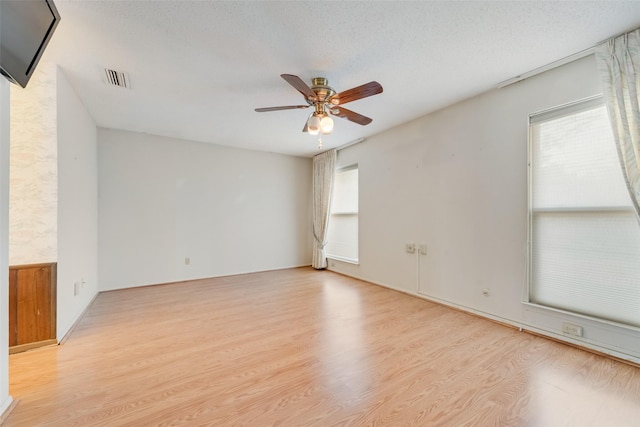 spare room featuring ceiling fan, light hardwood / wood-style flooring, and a textured ceiling