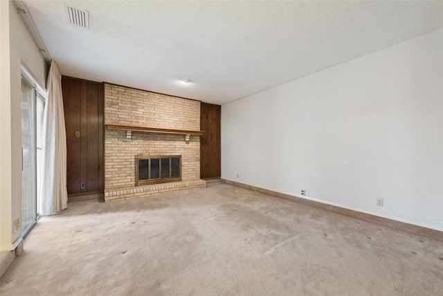 unfurnished living room with a brick fireplace, light carpet, and a textured ceiling