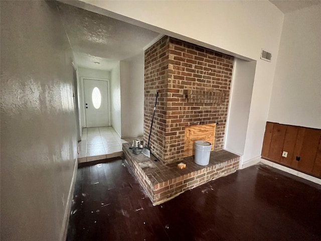 interior space with a brick fireplace, visible vents, and dark wood-style flooring