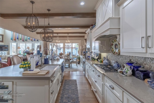 kitchen featuring pendant lighting, a spacious island, a notable chandelier, wood-type flooring, and white cabinets