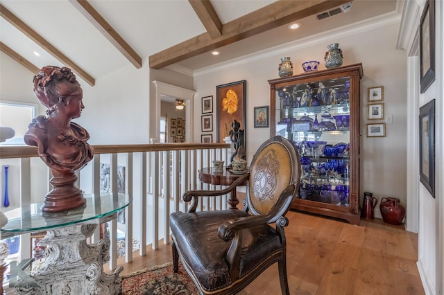 living area featuring ornamental molding, beamed ceiling, and light wood-type flooring