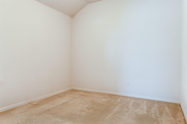 carpeted empty room with vaulted ceiling