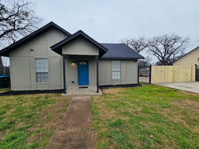 bungalow-style home featuring a gate, a front yard, fence, and a shingled roof