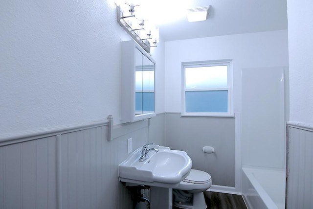 bathroom featuring sink, toilet, hardwood / wood-style flooring, and a washtub