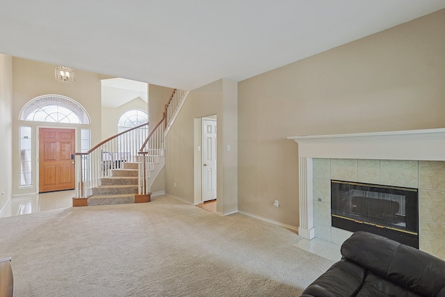 living area with lofted ceiling, light colored carpet, a tiled fireplace, baseboards, and stairs