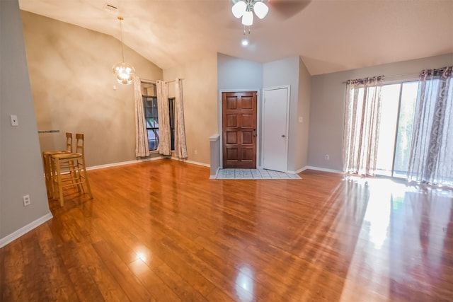 unfurnished living room with lofted ceiling, hardwood / wood-style floors, and ceiling fan with notable chandelier