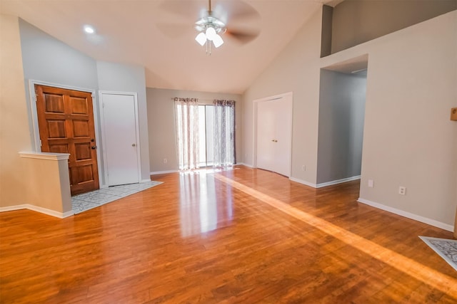 unfurnished living room with ceiling fan, high vaulted ceiling, and light hardwood / wood-style floors