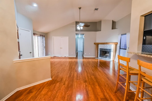 kitchen with a tiled fireplace, lofted ceiling, hardwood / wood-style floors, and ceiling fan