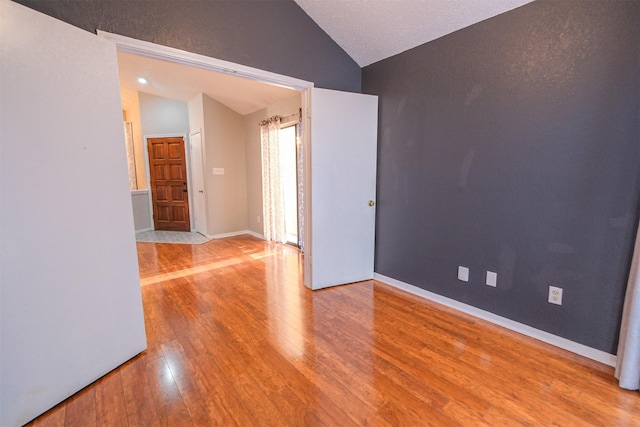 empty room with lofted ceiling and hardwood / wood-style floors