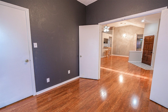 spare room featuring wood-type flooring, ceiling fan, and vaulted ceiling