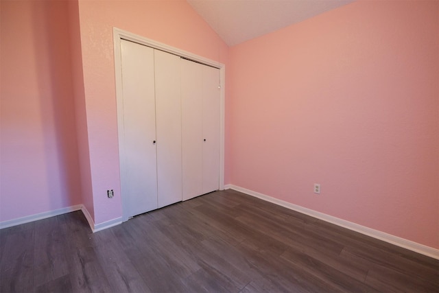 unfurnished bedroom featuring lofted ceiling, dark wood-type flooring, and a closet