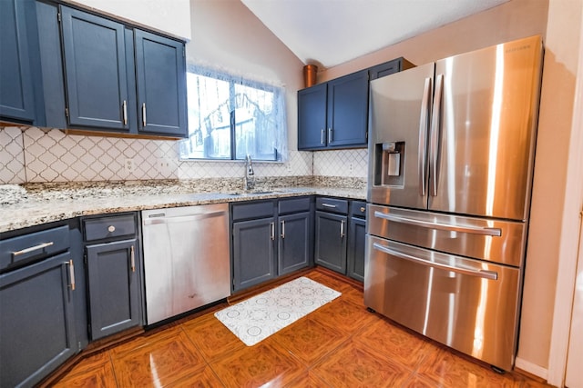 kitchen featuring vaulted ceiling, appliances with stainless steel finishes, blue cabinets, sink, and backsplash