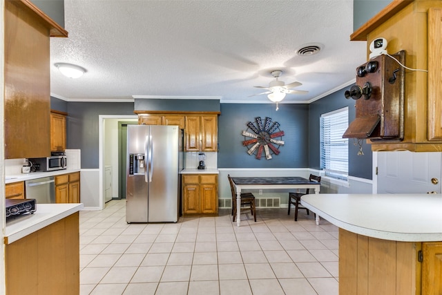 kitchen with ornamental molding, appliances with stainless steel finishes, light tile patterned flooring, and ceiling fan