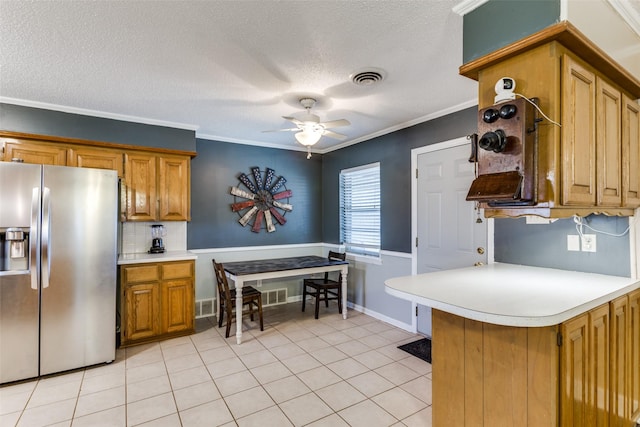 kitchen featuring ornamental molding, light tile patterned floors, stainless steel fridge, and kitchen peninsula