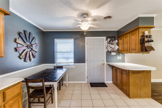 kitchen featuring ceiling fan, ornamental molding, kitchen peninsula, and a textured ceiling