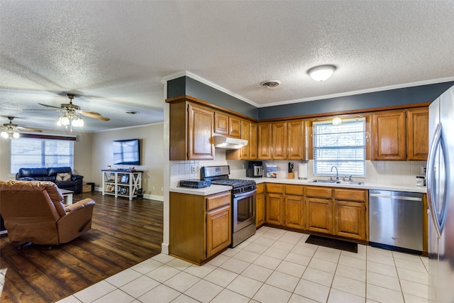 kitchen with crown molding, appliances with stainless steel finishes, sink, and backsplash