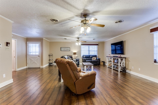 living room featuring dark hardwood / wood-style flooring, a textured ceiling, ornamental molding, and a healthy amount of sunlight