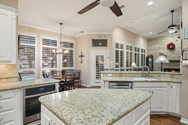 kitchen featuring white cabinetry, sink, light stone countertops, and oven