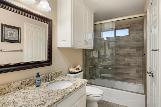 full bathroom featuring vanity, shower / bath combination with glass door, and toilet