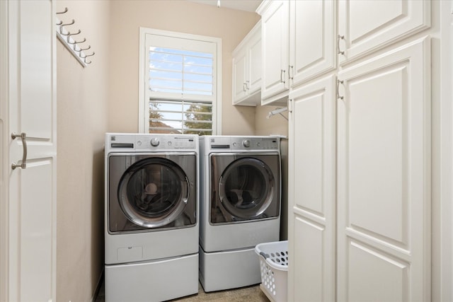 clothes washing area with washing machine and dryer and cabinets