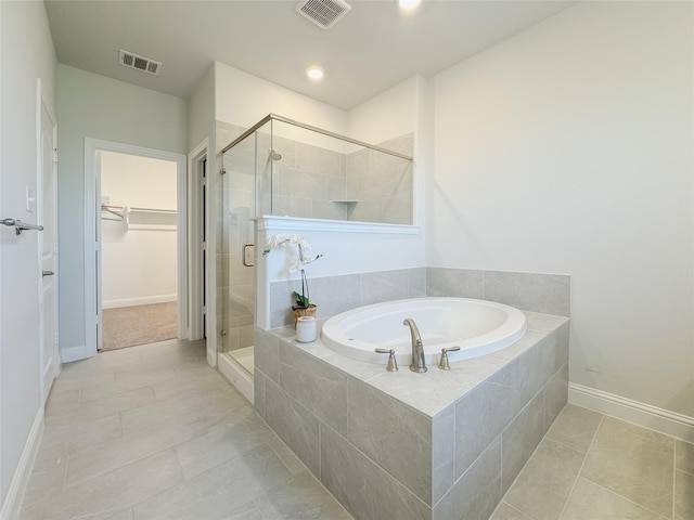 full bathroom featuring a garden tub, a spacious closet, visible vents, and a stall shower