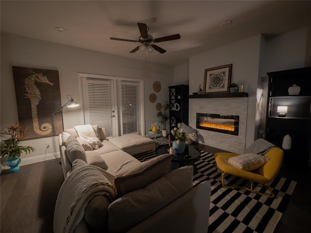 living area with a ceiling fan, baseboards, wood finished floors, and a glass covered fireplace