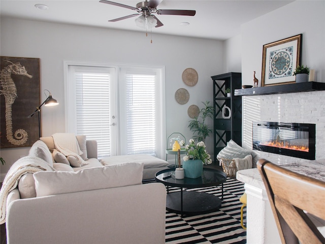 living area featuring a brick fireplace and ceiling fan