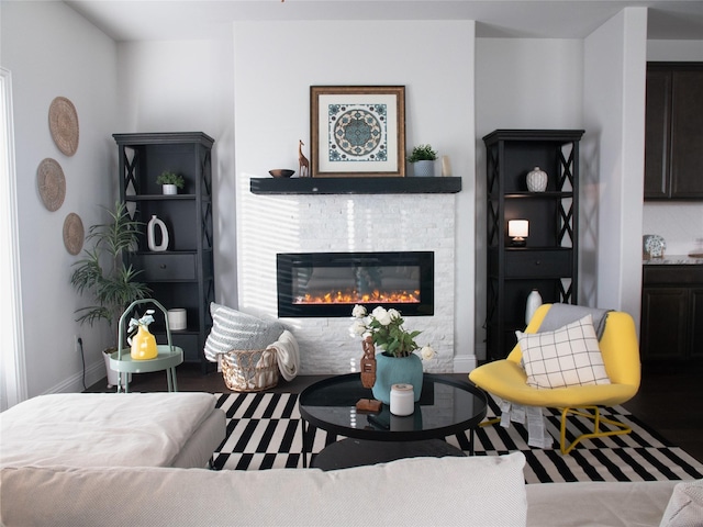 living room featuring a glass covered fireplace and baseboards