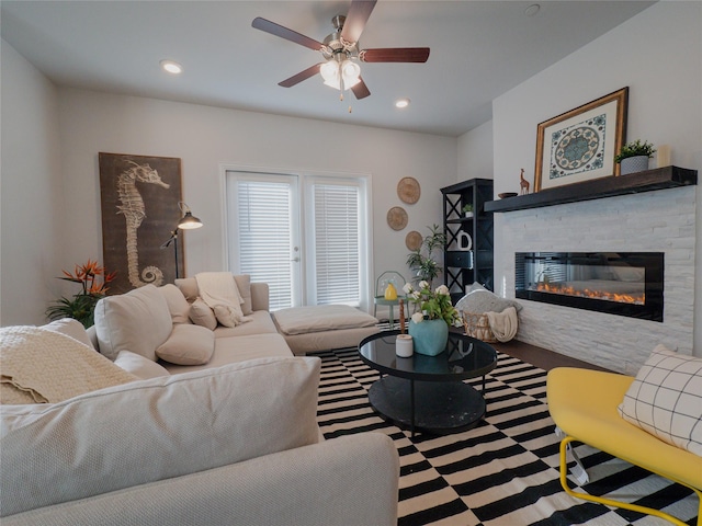 living area with ceiling fan, a stone fireplace, and recessed lighting