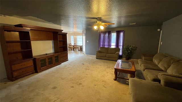 living room with ceiling fan, carpet floors, and a textured ceiling