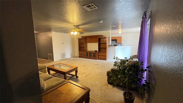 living room featuring ceiling fan, carpet flooring, and a textured ceiling