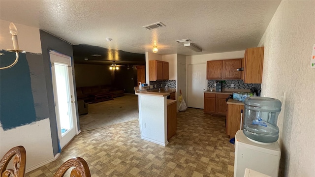 kitchen with decorative backsplash, kitchen peninsula, and a textured ceiling