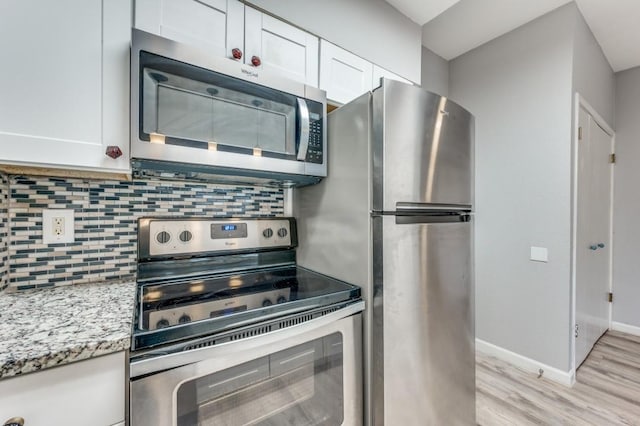 kitchen featuring white cabinetry, tasteful backsplash, light stone countertops, and appliances with stainless steel finishes