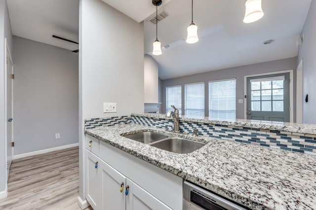 kitchen with hanging light fixtures, sink, white cabinets, and light stone counters