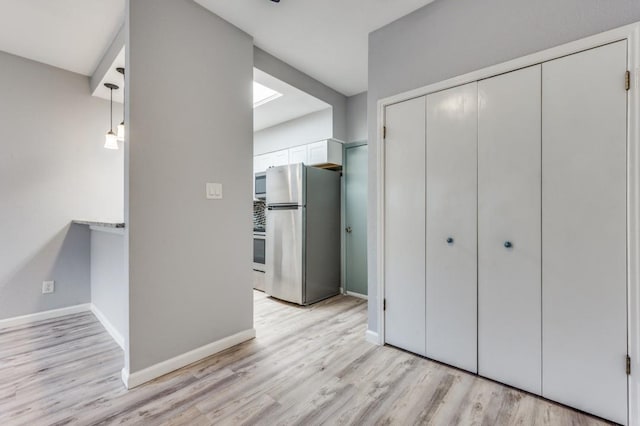 interior space featuring stainless steel refrigerator, a closet, and light hardwood / wood-style flooring