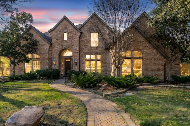 french provincial home featuring brick siding and a front lawn