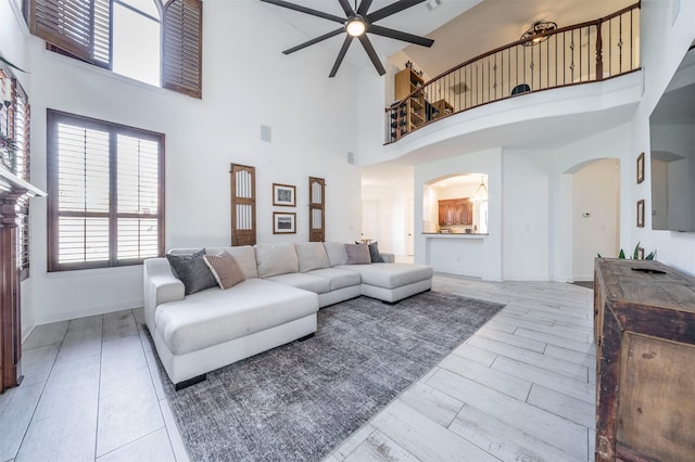 720 Amistad Dr, Prosper, TX 75078 - living area with a ceiling fan, a high ceiling, arched walkways, wood tiled floors, and baseboards