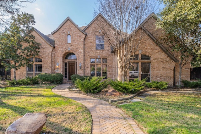 tudor home with brick siding and a front lawn