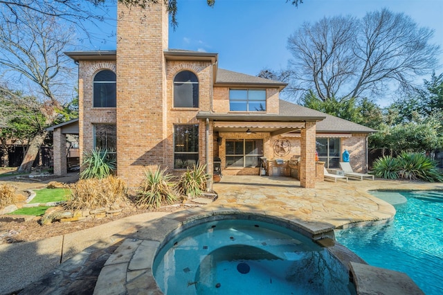 720 Amistad Dr, Prosper, TX 75078 - rear view of house featuring brick siding, a patio area, a chimney, and a pool with connected hot tub
