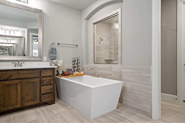 bathroom featuring vanity, shower with separate bathtub, and tile walls