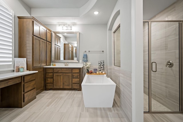 bathroom featuring vanity, tile walls, and separate shower and tub