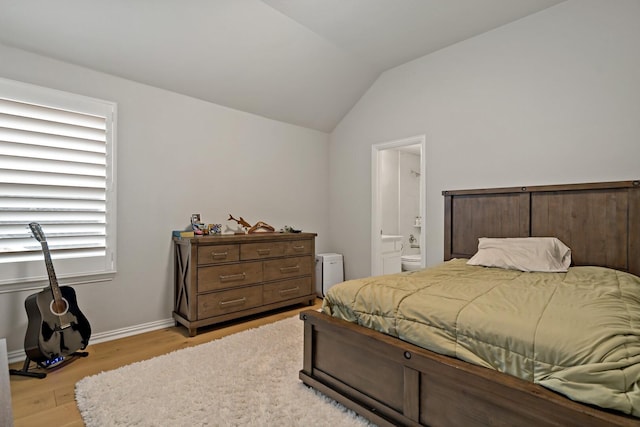 bedroom featuring lofted ceiling, ensuite bath, and light hardwood / wood-style flooring