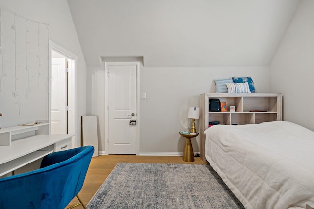 bedroom with vaulted ceiling and light hardwood / wood-style flooring