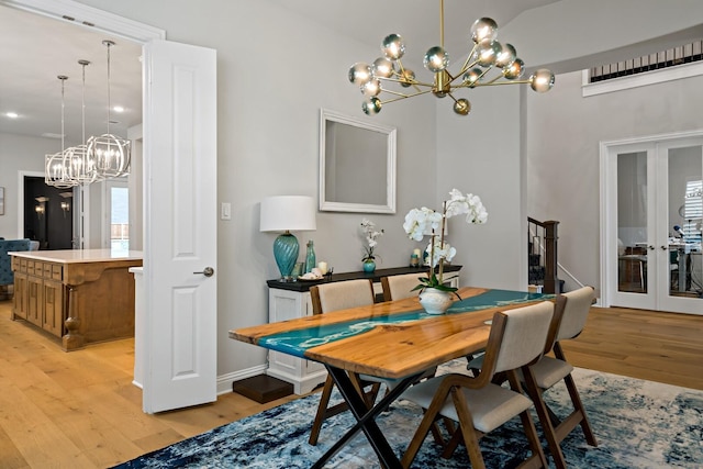 dining space featuring french doors, a chandelier, and light wood-type flooring